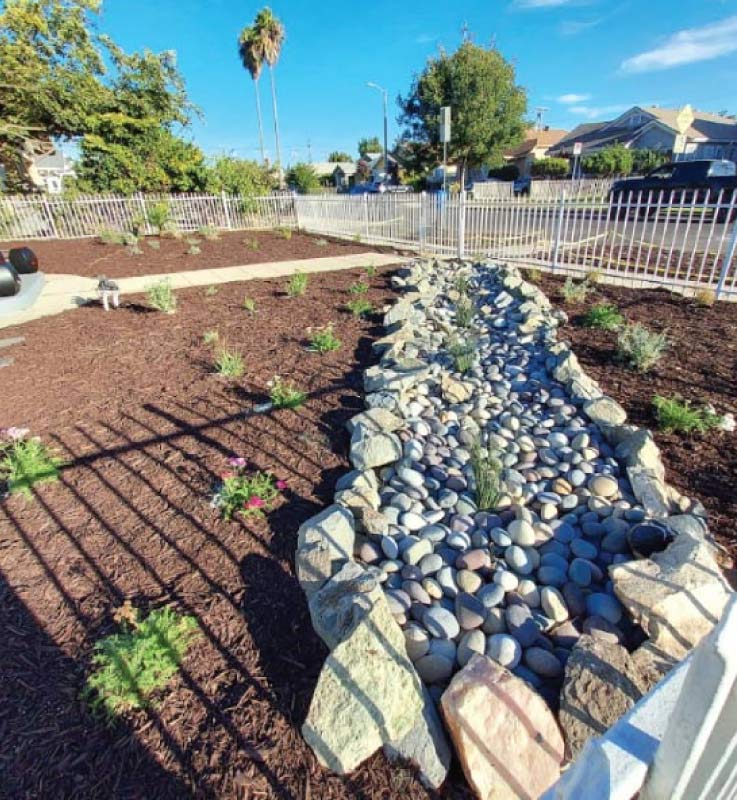 Newly installed erosion control BMPs featuring a river rock swale and mulch to assist with residential stormwater management.