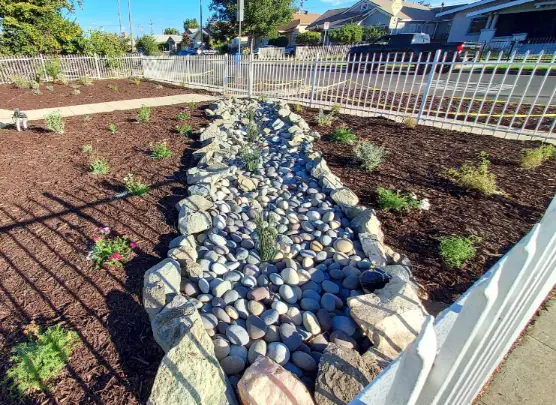 L.I.D. compliant dry river bed and vegetated bioswale with river rock for stormwater management.